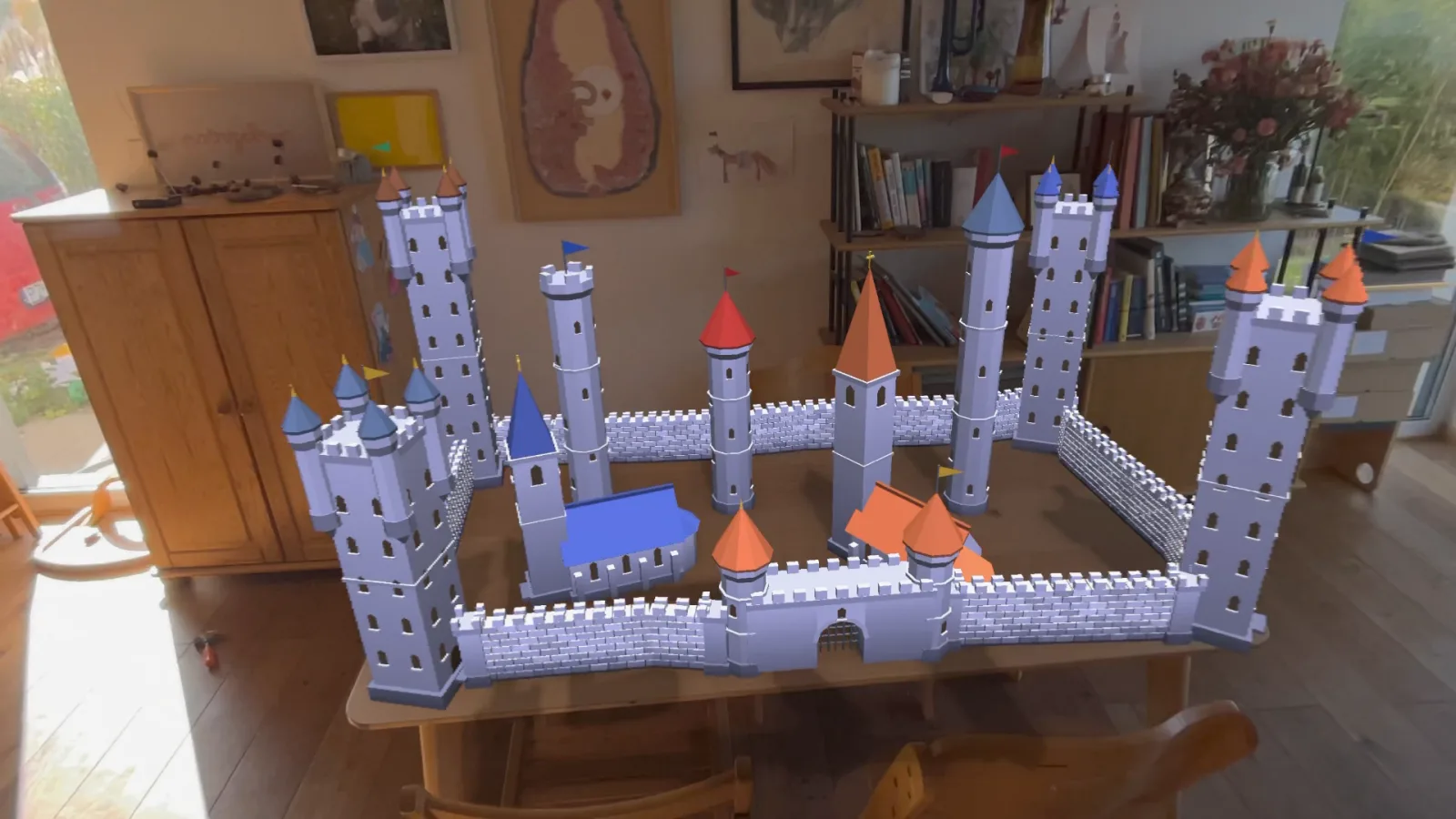 A finished castle with towers and walls standing on a real wooden table in a living room
