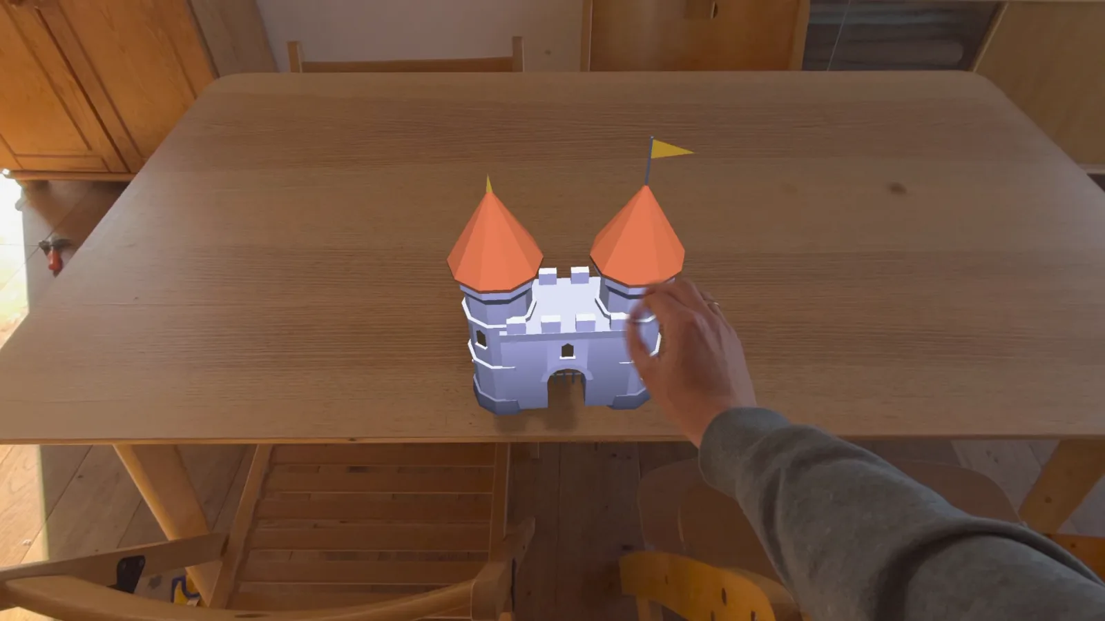 A hand pinching above a wooden table as a castle gatehouse appears